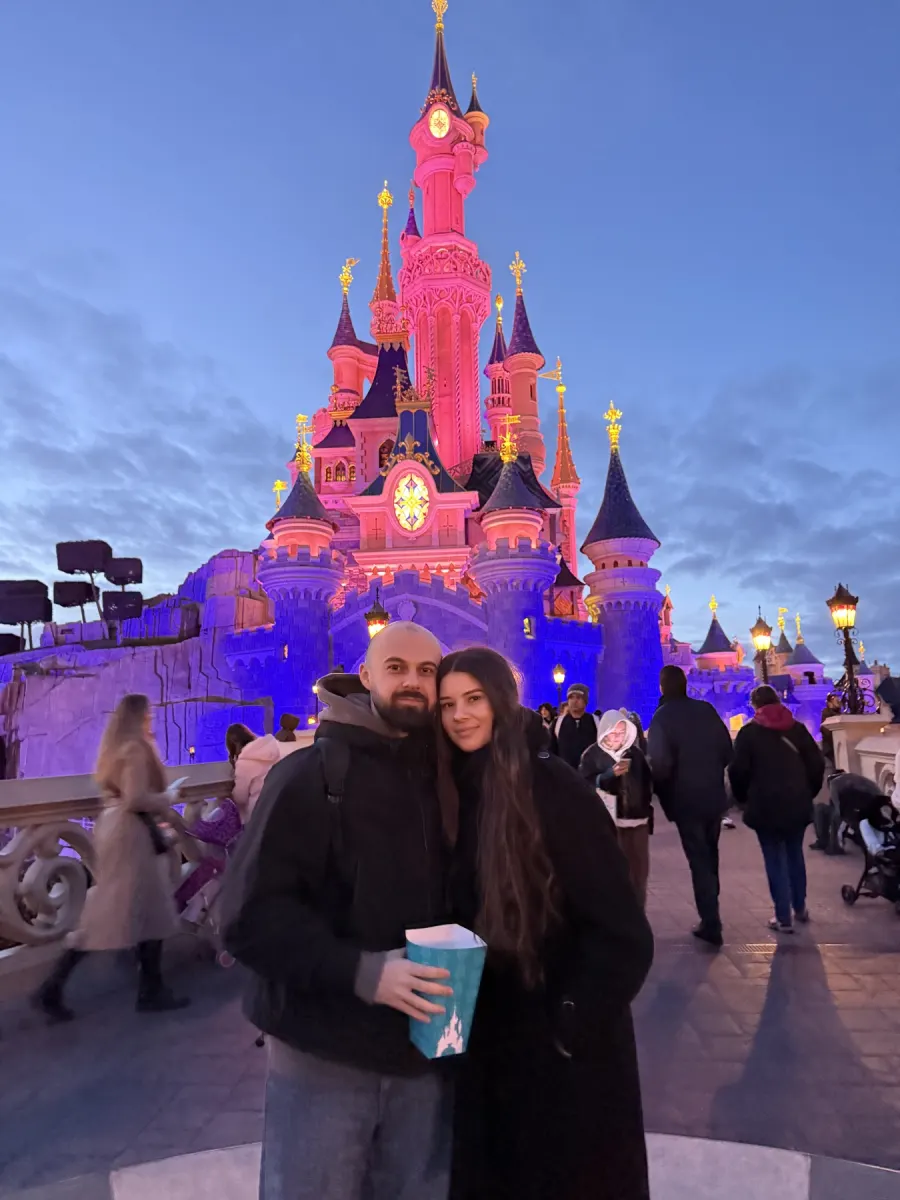 Cristi and Diana in front of the Disneyland Paris castle at dusk