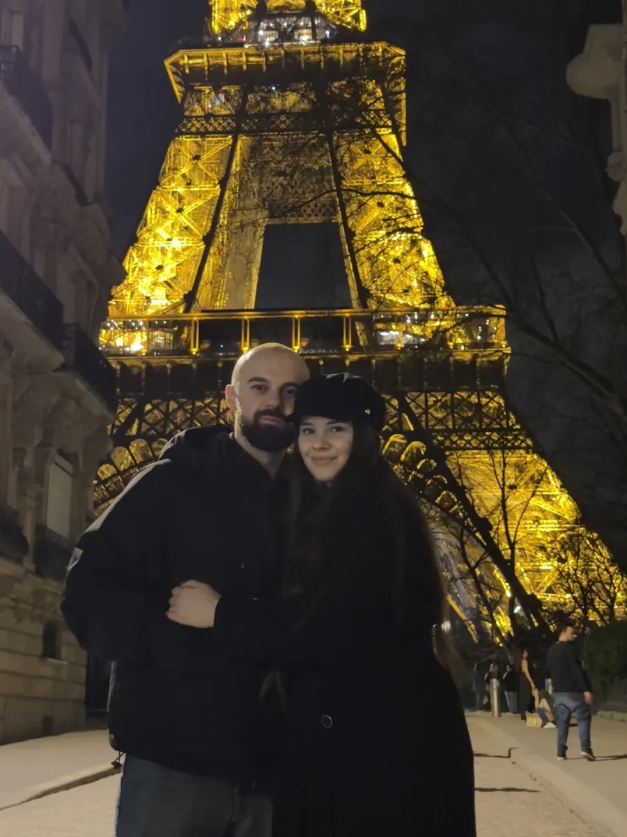 Cristi and Diana under the lit-up Eiffel Tower at night
